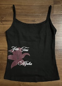 a black tank top with a pink flower on it